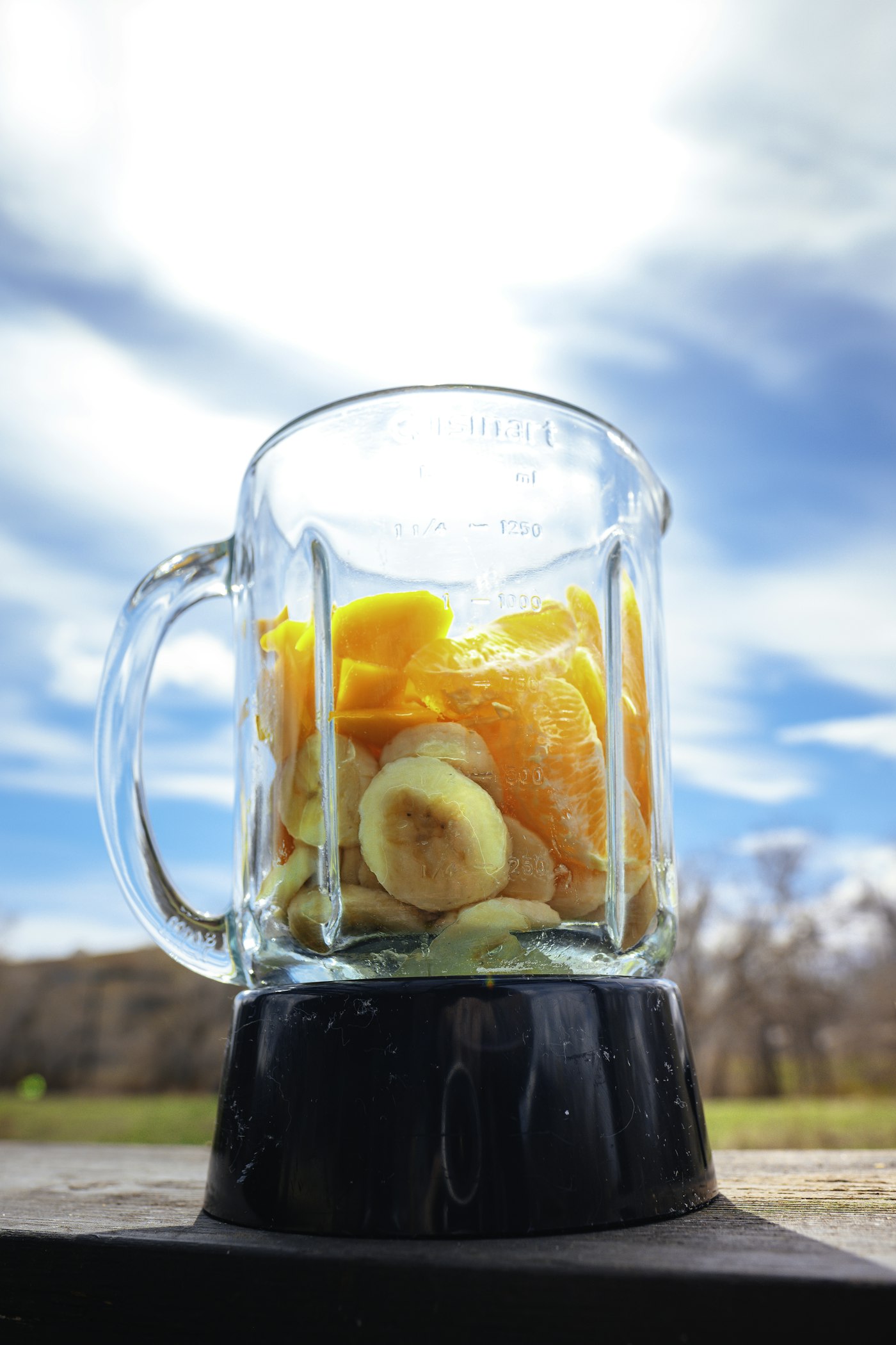 Glass blender jug filled with fruit, photographed outdoors